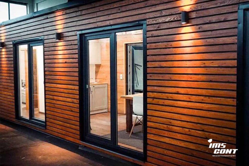 Kúpený a upravený lodný kontajner od IMS cont využitý ako moderný obytný priestor s dreveným obkladom a presklenými dverami.